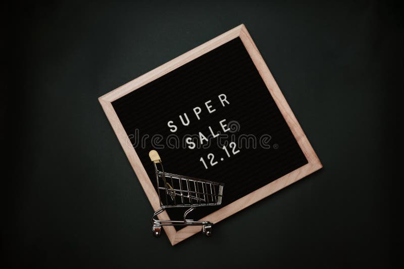 The text of the sale 12.12 on a letter board with a mini grocery cart. Design to promote the winter sale at the end of the year. Top view. Solid green background. The text of the sale 12.12 on a letter board with a mini grocery cart. Design to promote the winter sale at the end of the year. Top view. Solid green background.