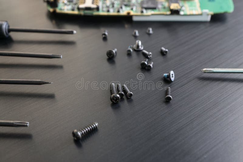 O tiro do close up de um preto parafusa e desmontou o smartphone na superfície do preto imagens de stock O tiro do close up de um preto parafusa e desmontou o smartphone na superfície do preto imagens de stock