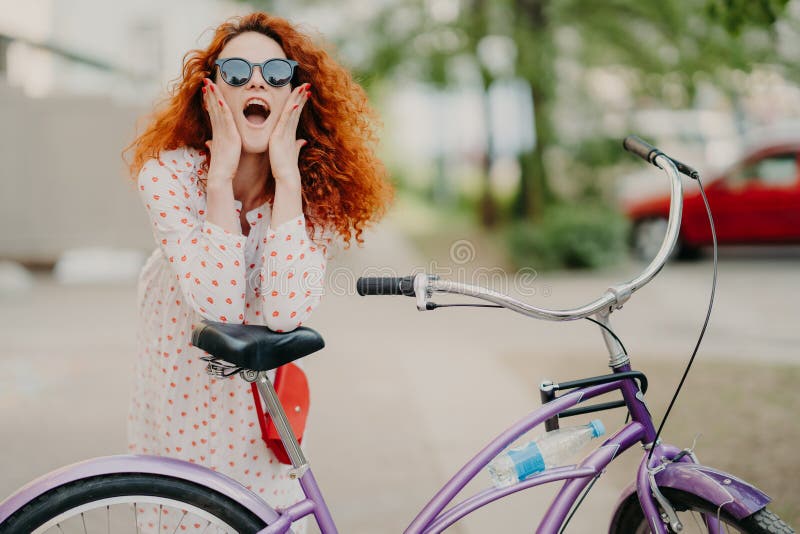 O tiro horizontal da bicicleta feliz dos passeios da mulher no parque, tem a ruptura, levanta na c?mera, mant?m a boca aberta, to fotos de stock royalty free O tiro horizontal da bicicleta feliz dos passeios da mulher no parque, tem a ruptura, levanta na c?mera, mant?m a boca aberta, to fotos de stock royalty free