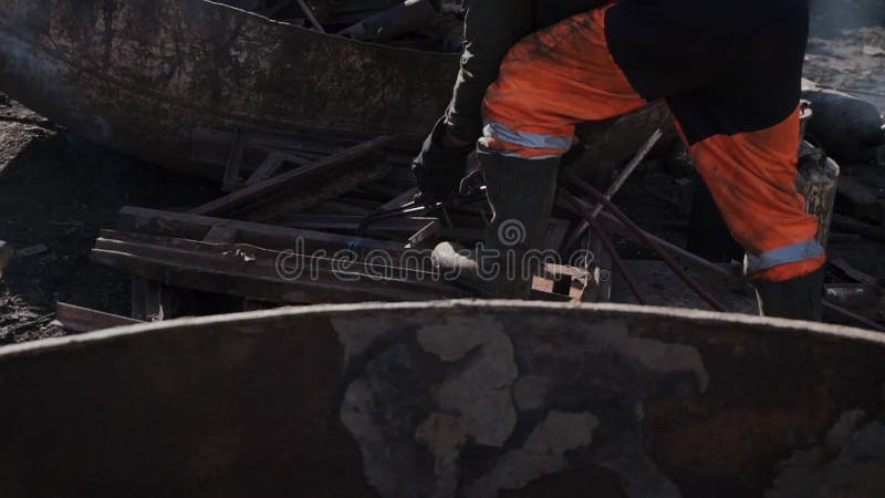 O trabalhador corta o metal oxidado com um cortador do gás