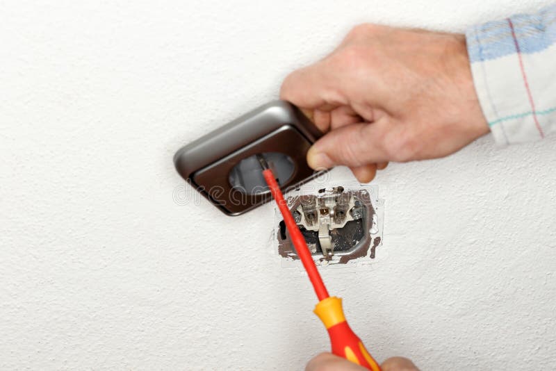 O trabalhador está reparando um soquete da tomada imagens de stock O trabalhador está reparando um soquete da tomada imagens de stock