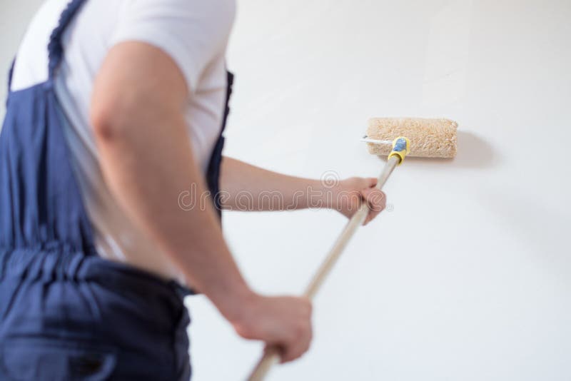 O trabalhador profissional do pintor está pintando uma parede