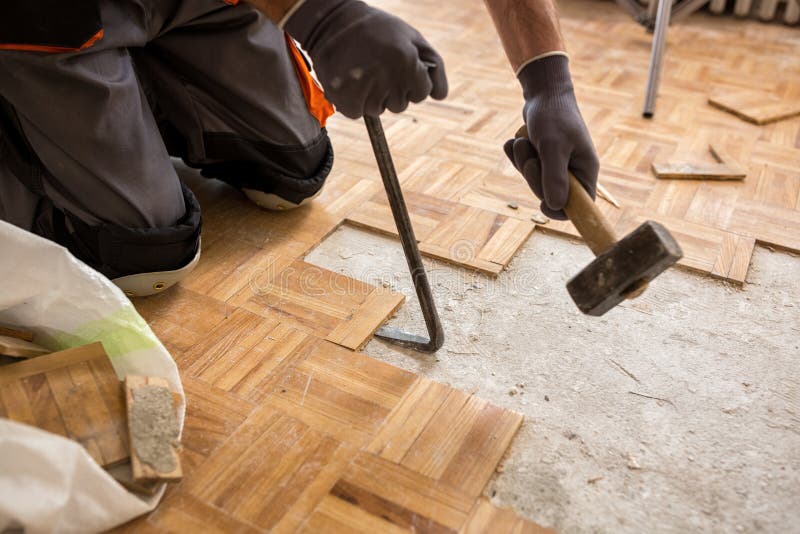 O trabalhador remove o fparquet velho, casa da renovação fotografia de stock O trabalhador remove o fparquet velho, casa da renovação fotografia de stock
