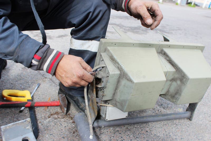 O trabalhador substitui o sinal quebrado com um sinal de trabalho Desaparafusando partes com as lâmpadas da asseguração foto de stock O trabalhador substitui o sinal quebrado com um sinal de trabalho Desaparafusando partes com as lâmpadas da asseguração foto de stock