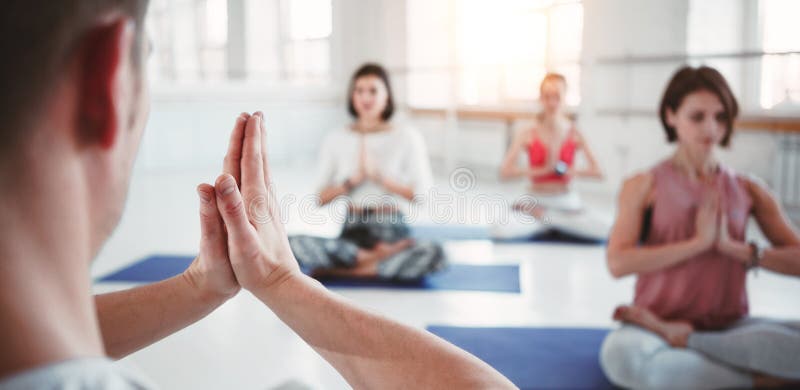 O treinador do homem treina o grupo de exercícios da ioga das mulheres para cuidados médicos de manutenção na classe branca Dos p imagens de stock royalty free O treinador do homem treina o grupo de exercícios da ioga das mulheres para cuidados médicos de manutenção na classe branca Dos p imagens de stock royalty free