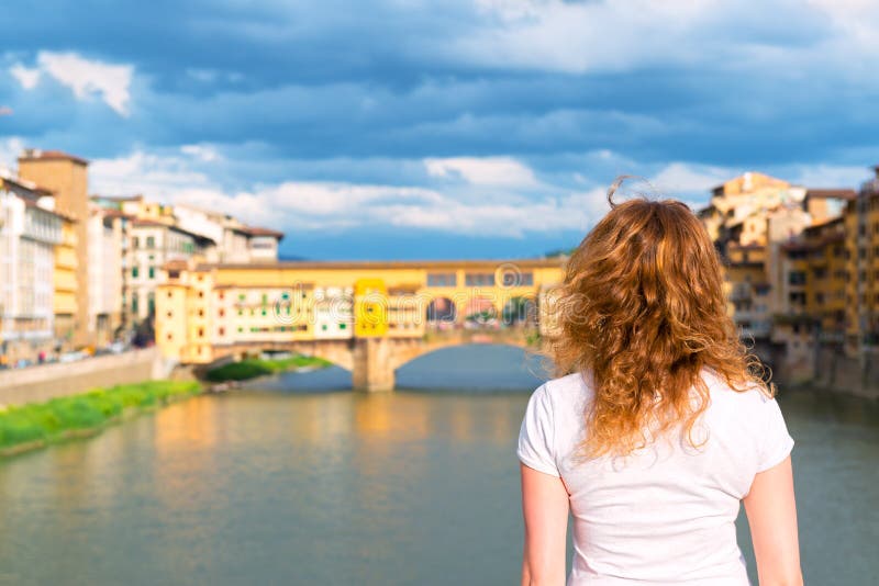 O turista fêmea novo olha o Ponte Vecchio em Florença fotos de stock royalty free O turista fêmea novo olha o Ponte Vecchio em Florença fotos de stock royalty free