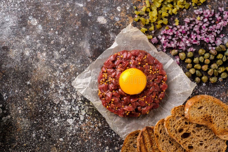 O tártaro fresco da carne é servido com gema, pão fritado, cucu conservado fotografia de stock O tártaro fresco da carne é servido com gema, pão fritado, cucu conservado fotografia de stock