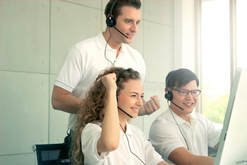 O tânără frumoasă și zâmbitoare fericită, cu căști, care lucrează la un consultant de la centrul de apeluri, și-a ridicat mâna și royalty free stock photo
