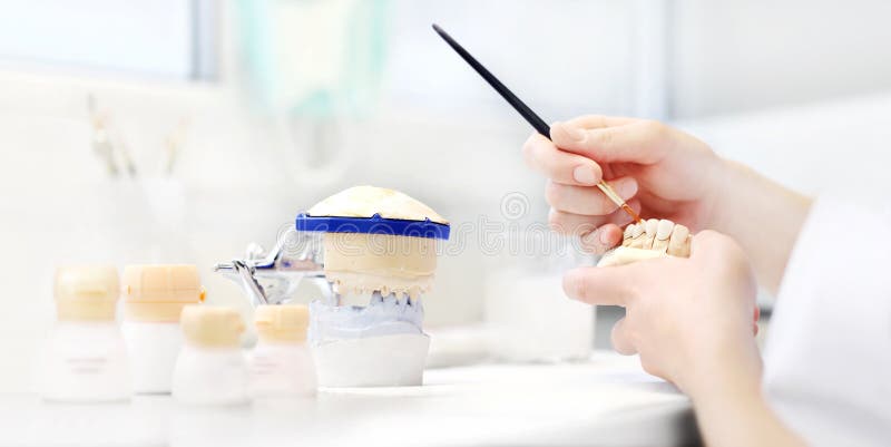 O técnico dental entrega o trabalho com as dentaduras do dente em seu trabalho fotos de stock O técnico dental entrega o trabalho com as dentaduras do dente em seu trabalho fotos de stock