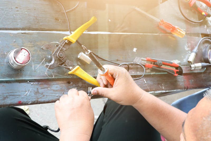 O técnico Men da eletrônica está reparando dispositivos elétricos Conexão de fios quebrados com as máquinas de solda imagens de stock O técnico Men da eletrônica está reparando dispositivos elétricos Conexão de fios quebrados com as máquinas de solda imagens de stock