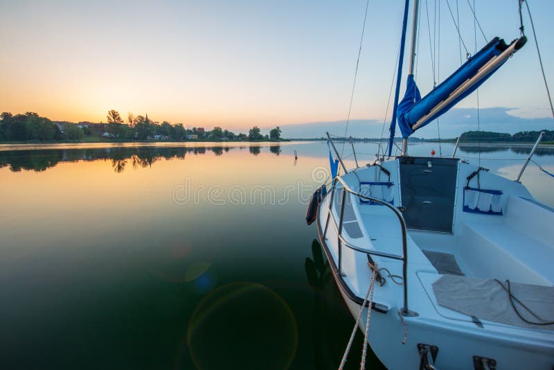 Small sailboat during sunrise are docking at Powidzkie lake in Poland. Small sailboat during sunrise are docking at Powidzkie lake in Poland.