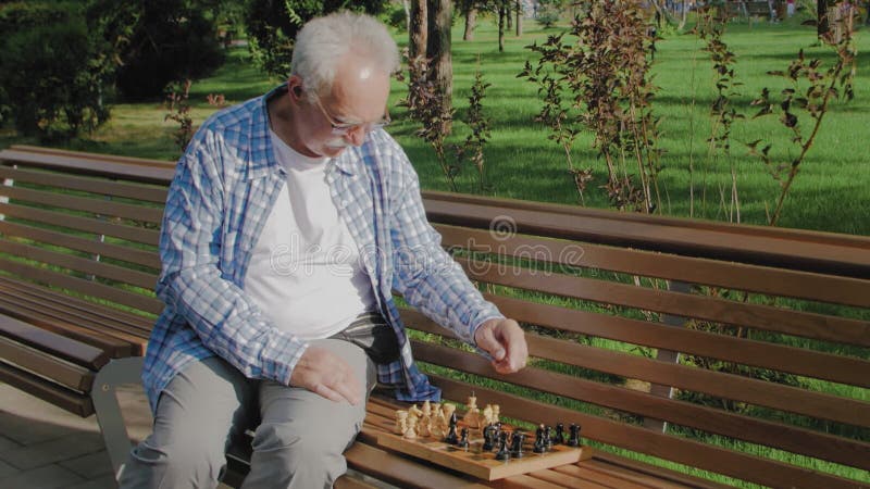 Homem idoso jogando xadrez sozinho e olhando para a câmera se preparando  para a competição, Banco de Video - Envato Elements