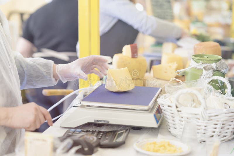 O vendedor pesa a parte de queijo fresco do fazendeiro no mercado de produtos orgânicos, foco seletivo Produto de leiteria gastro imagens de stock royalty free O vendedor pesa a parte de queijo fresco do fazendeiro no mercado de produtos orgânicos, foco seletivo Produto de leiteria gastro imagens de stock royalty free