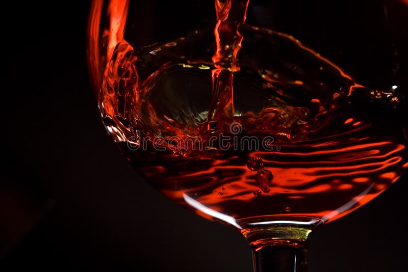 O vinho vermelho derrama em um vidro foto de stock O vinho vermelho derrama em um vidro foto de stock
