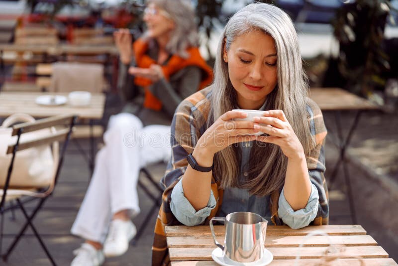 Oaspeții de la cafenele seniori se concentrează pe o doamnă cu părul frumos și păr de argint care ține paharul de băutură royalty free stock image