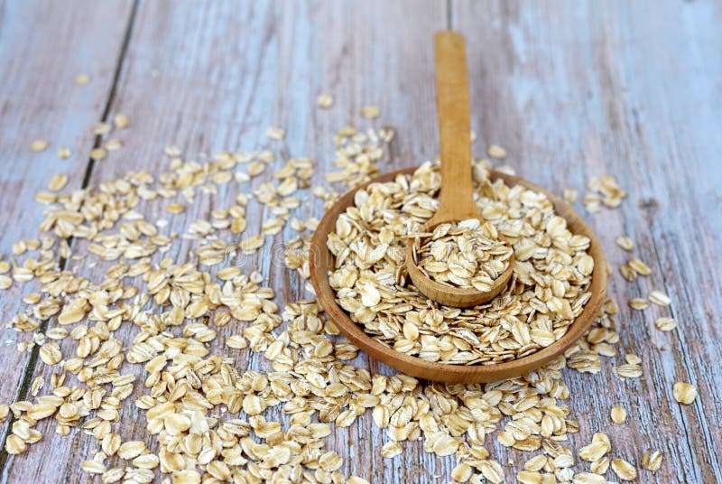 Oat Flakes Uncooked in Wooden Bowl with Spoon on Rustic Table. Concept ...