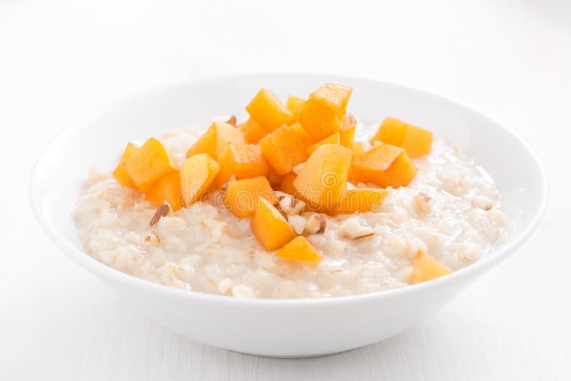 Oatmeal z świeżymi morelami i dokrętkami na białym drewnianym stole obrazy stock Oatmeal z świeżymi morelami i dokrętkami na białym drewnianym stole obrazy stock