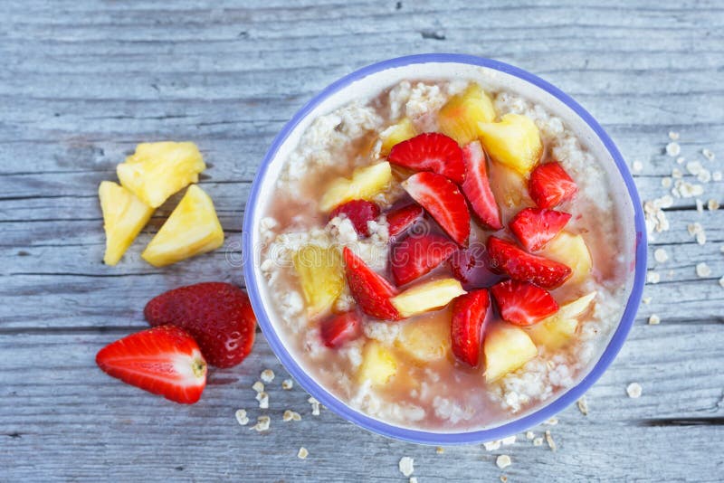 Oatmeal κουάκερ σε ένα κύπελλο με τις φρέσκους φράουλες και τους ανανάδες στοκ φωτογραφία με δικαίωμα ελεύθερης χρήσης Oatmeal κουάκερ σε ένα κύπελλο με τις φρέσκους φράουλες και τους ανανάδες στοκ φωτογραφία με δικαίωμα ελεύθερης χρήσης