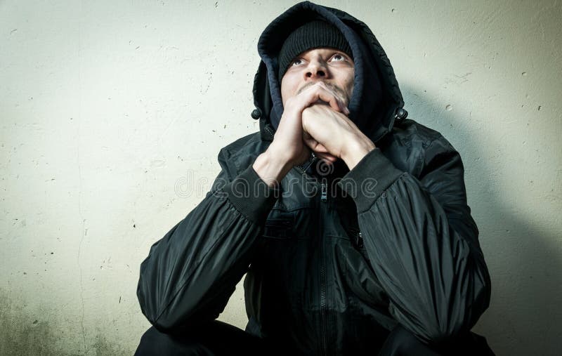 Obdachlose Manndroge und Alkoholsüchtiger allein sitzend und deprimiert auf der Straße in der Winterkleidung, die besorgtes kalte stockbilder Obdachlose Manndroge und Alkoholsüchtiger allein sitzend und deprimiert auf der Straße in der Winterkleidung, die besorgtes kalte stockbilder