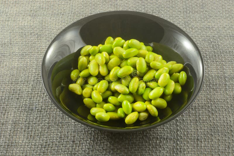 Obehandlad edamame i svart skål arkivbild