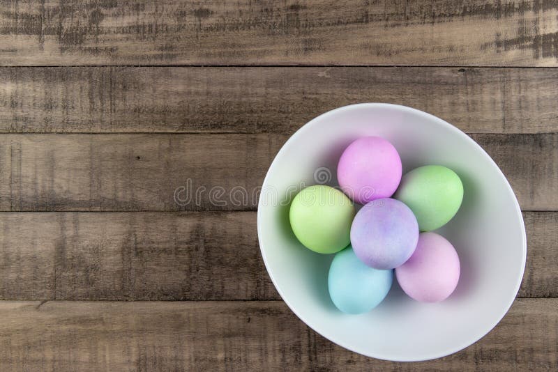 Obenliegende Ansicht von gemalten Pastellostereiern in einer weißen Schüssel auf rustikaler Bauernhoftabelle stockfoto Obenliegende Ansicht von gemalten Pastellostereiern in einer weißen Schüssel auf rustikaler Bauernhoftabelle stockfoto