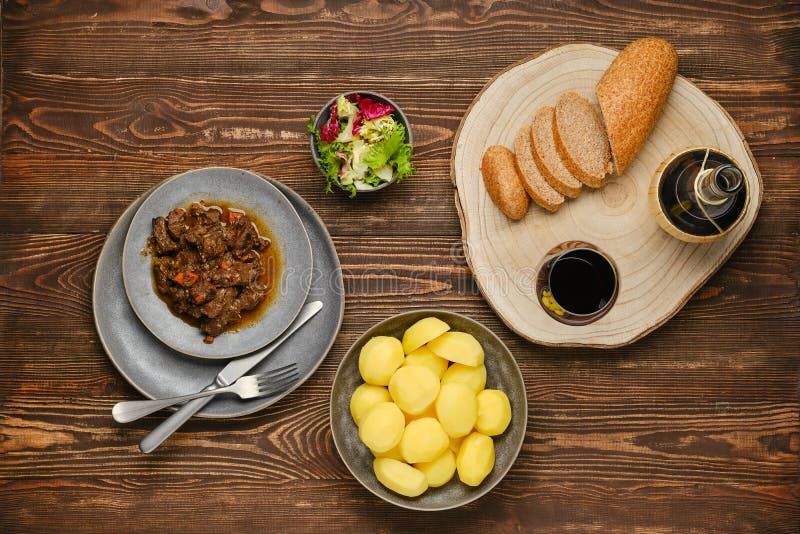 Obenliegende Auffassung des Rindfleischragouts mit Kartoffelsalat und -wein stockbilder
