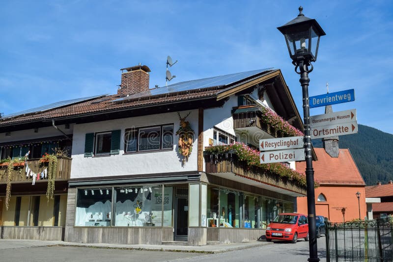 OBERAMMERGAU, GERMANY - OKTOBER 09, 2018: Old lamppost with direction signs and an old building with balconies on street royalty free stock photography OBERAMMERGAU, GERMANY - OKTOBER 09, 2018: Old lamppost with direction signs and an old building with balconies on street royalty free stock photography