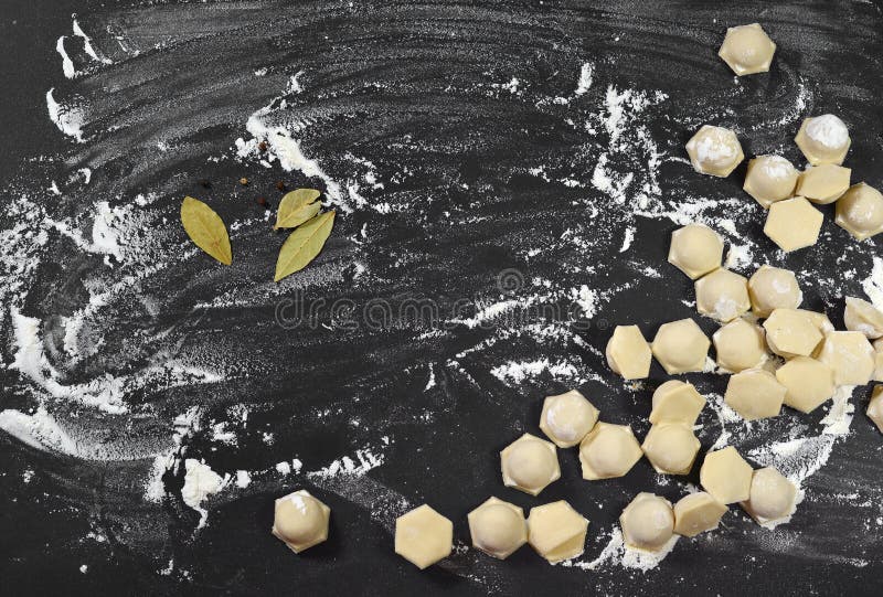 Oberedda dumplag, deg ravioli, på en svart baksida som är sprinklad med mjöl. royaltyfri bild