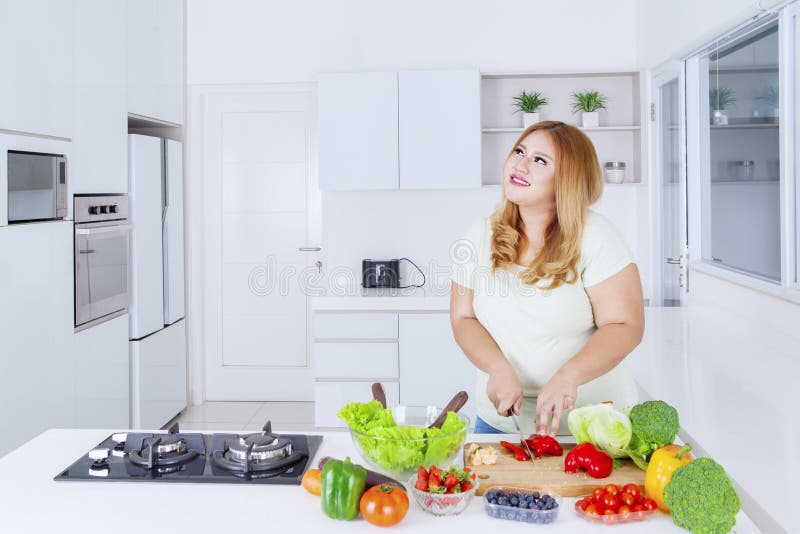Obese kvinna som bereder grönsaksframställning arkivfoto