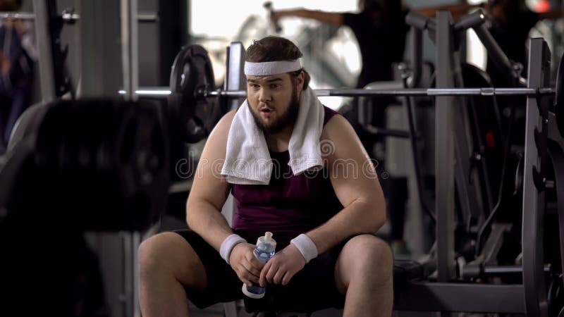 Obese male drinking water after barbell exercise, restoring aqua balance, diet, stock photo