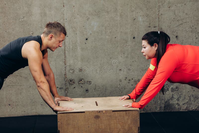 Obese woman and fit man doing push-ups at gym royalty free stock photo Obese woman and fit man doing push-ups at gym royalty free stock photo