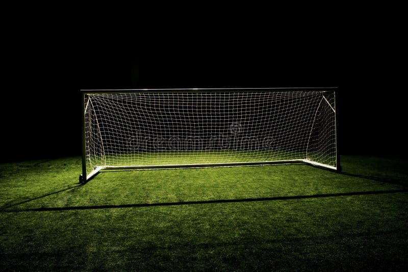 A soccer goal or football goal with a simple black backdrop isolated from the darkness with spotlight lighting. A soccer goal or football goal with a simple black backdrop isolated from the darkness with spotlight lighting