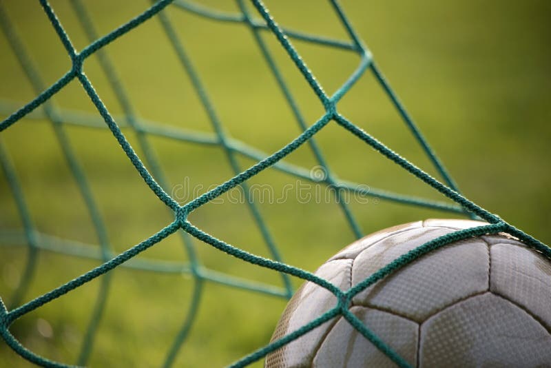 Goal! Golden football in goal net in the evening sun. Goal! Golden football in goal net in the evening sun.