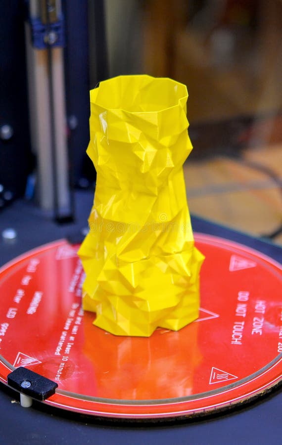 The object in the form of a yellow vase stands on the desktop of a three-axis 3d printer royalty free stock image