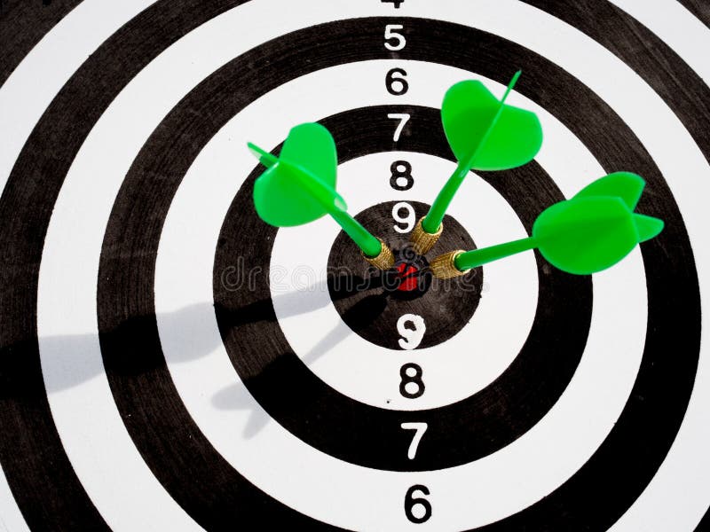 Objetivo con tres dardos verdes enfocados en el ojo del toro, Fijando objetivos de negocio desafiantes y listos para alcanzar el o