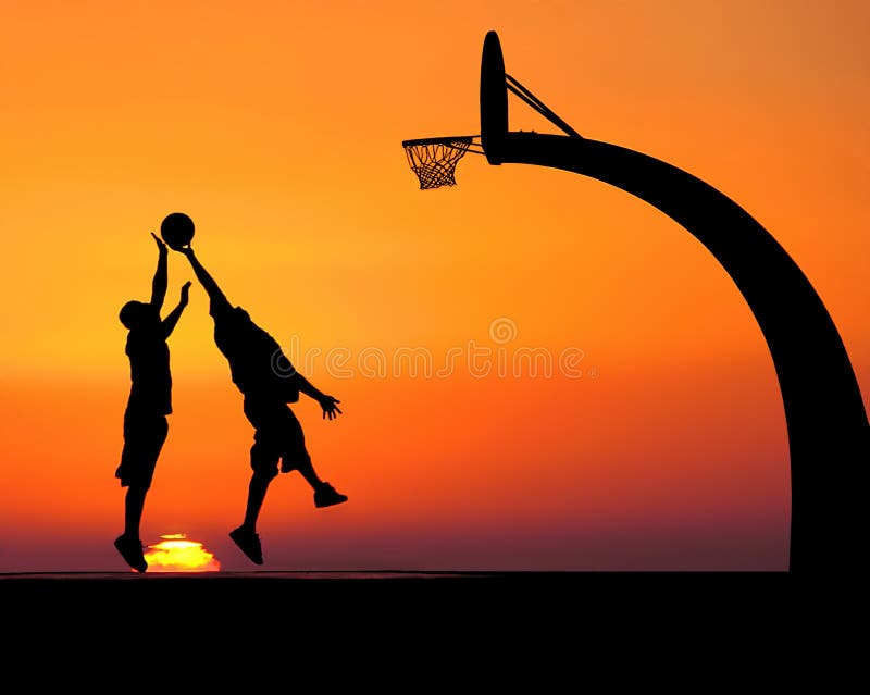 Two young men playing basketball, silhouetted against a majestic sunset. Two young men playing basketball, silhouetted against a majestic sunset.