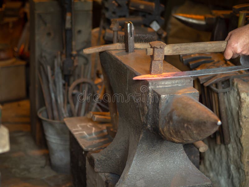Obsługuje kowalstwo gorący kawałek metal na kowadle obraz stock Obsługuje kowalstwo gorący kawałek metal na kowadle obraz stock