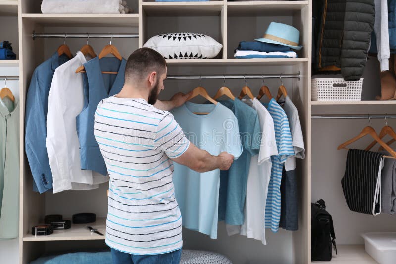 Man choosing outfit from large wardrobe closet with stylish clothes and home stuff. Man choosing outfit from large wardrobe closet with stylish clothes and home stuff