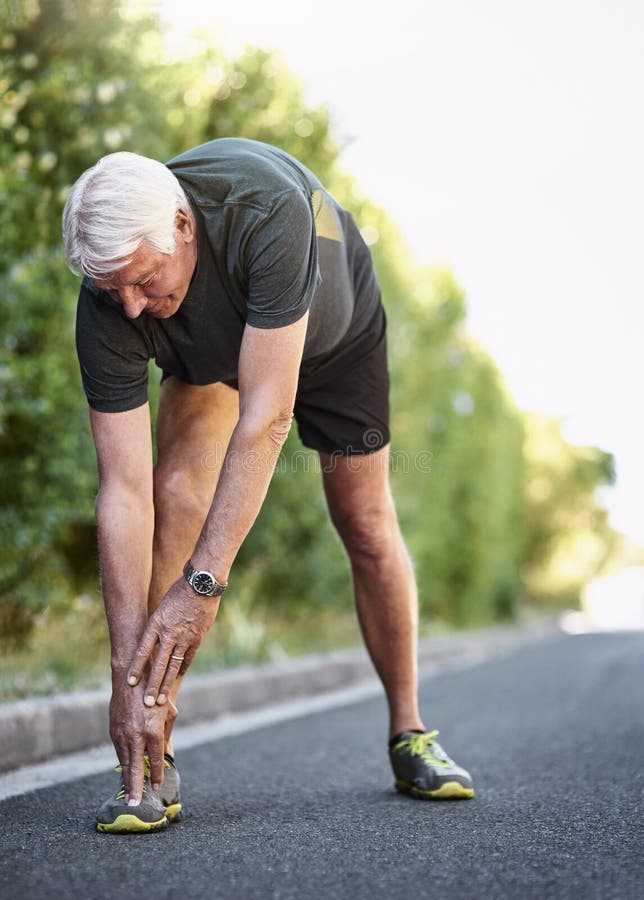 Obtener un buen warmup es vital para una gran entrenamiento. un anciano calentándose antes de salir corriendo. fotos de archivo