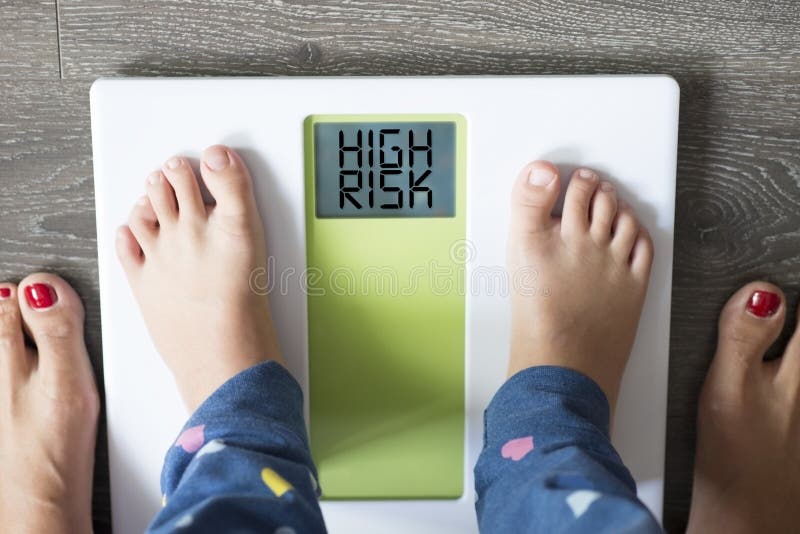 Obésité d'enfance à haut risque pour des problèmes de santé avec des pieds de childâ€™s sur l'échelle de poids sous la direction