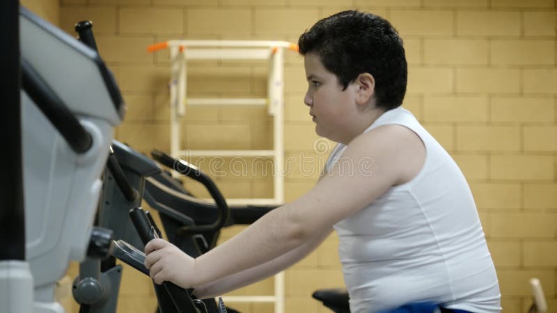 Obésité peu de garçon d'enfant formant le vélo stationnaire dans le gymnase Mode de vie sain de concept