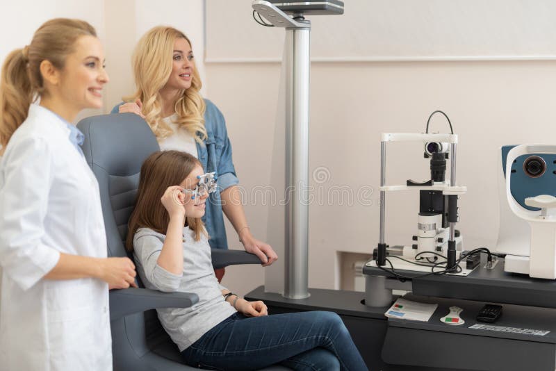Occhi d'esame del bambino dell'optometrista con la struttura di prova ottica fotografia stock libera da diritti Occhi d'esame del bambino dell'optometrista con la struttura di prova ottica fotografia stock libera da diritti