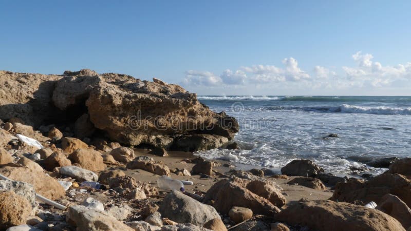 Oceaan rotsachtig die strand met plastic huisvuil wordt verontreinigd Aardeverontreiniging