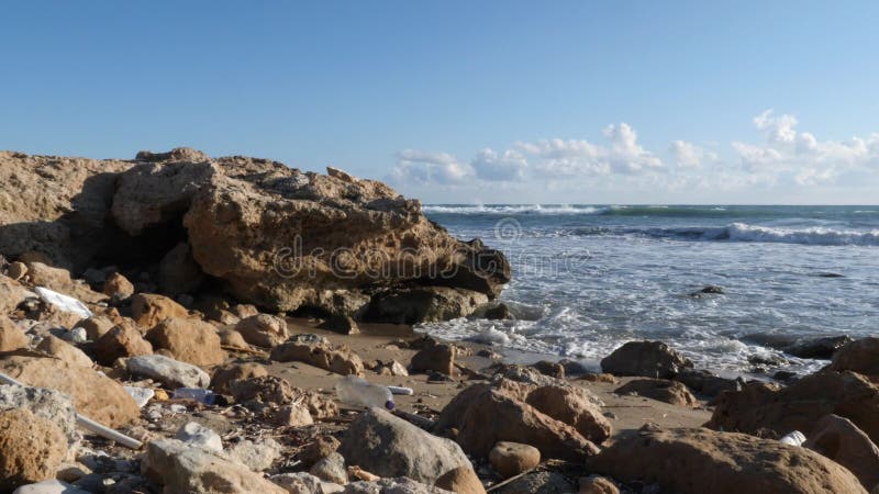 Oceaan rotsachtig die strand met plastic huisvuil wordt verontreinigd Aardeverontreiniging Langzame Motie