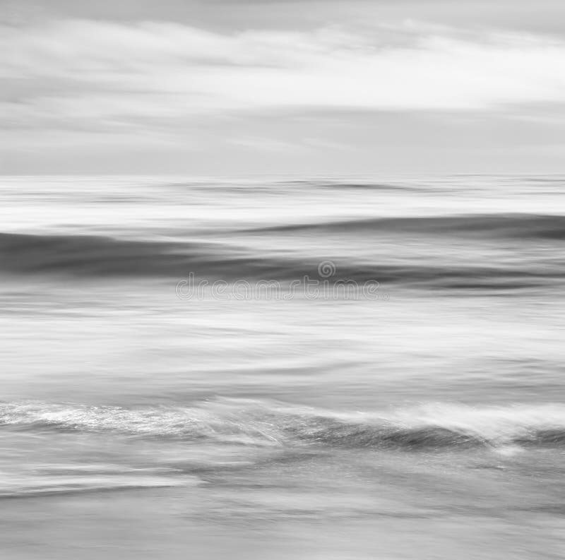 An abstract, black and white seascape featuring converging ocean waves. Image made with panning motion and a long exposure for a soft, blurred effect. An abstract, black and white seascape featuring converging ocean waves. Image made with panning motion and a long exposure for a soft, blurred effect.