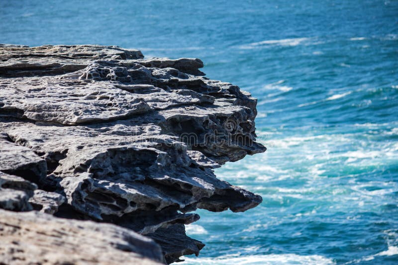 Oceanside rocky cliff top with blue coastal sea in background