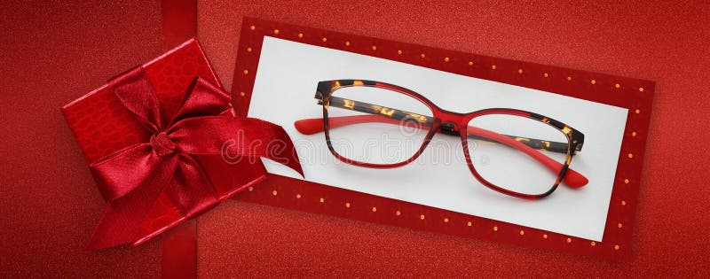 Ochelari: cutie roșie pentru card de Crăciun fericit cu panglică lucioasă, cu foi de formă roșie pentru arcuș, izolate pe partea s stock photos