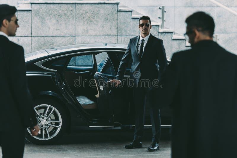 ochroniarz w okularach przeciwsłonecznych otwiera samochodowego drzwi obraz stock ochroniarz w okularach przeciwsłonecznych otwiera samochodowego drzwi obraz stock