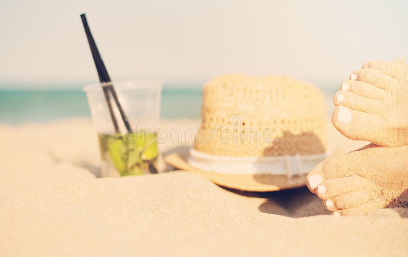 Ocio en el verano - hermoso de pies atractivos de las mujeres, de piernas femeninas en la playa arenosa con el sombrero y del cóc fotos de archivo libres de regalías Ocio en el verano - hermoso de pies atractivos de las mujeres, de piernas femeninas en la playa arenosa con el sombrero y del cóc fotos de archivo libres de regalías