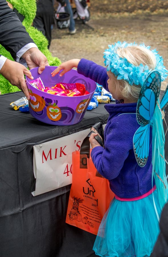 little girl dressed as a fairy takes candy during an outdoor Halloween event stock photo little girl dressed as a fairy takes candy during an outdoor Halloween event stock photo